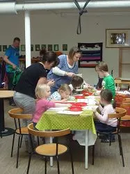 Kinder und Erwachsene basteln gemeinsam an einem Tisch