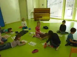 Kinder sitzen im Morgenkreis mit Bildkarten auf dem Boden